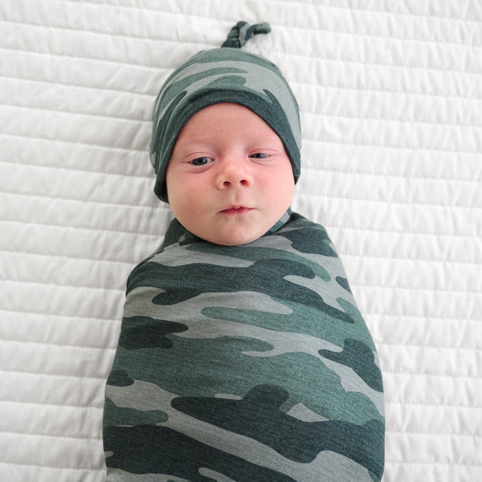 Top view image of baby laying down in the Vintage Camo Swaddle & Hat Set