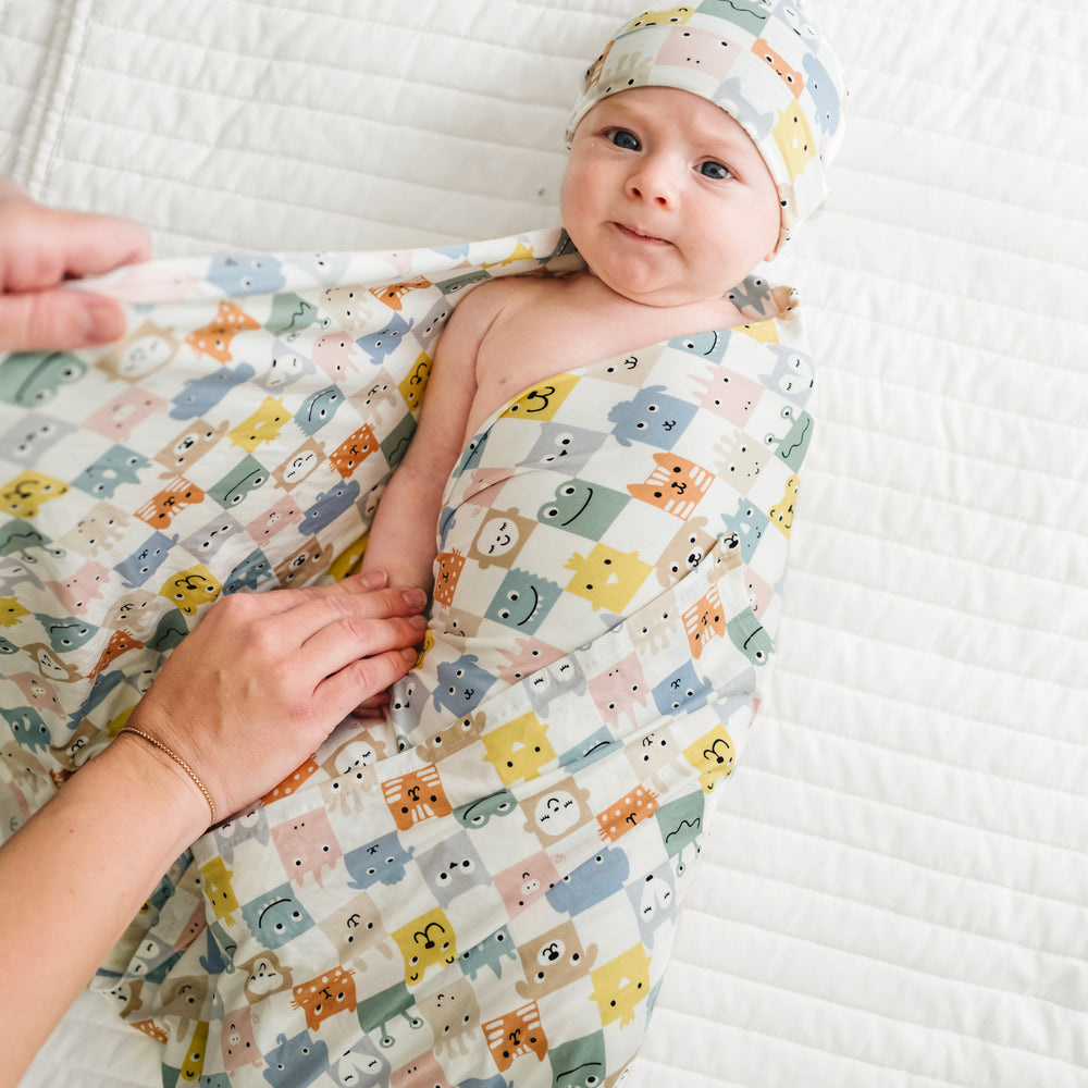 Child being swaddled in a Check Mates swaddle and hat set
