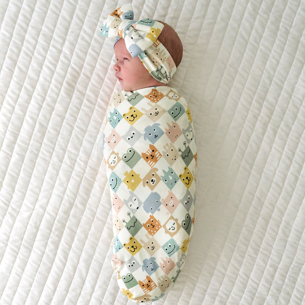 Infant swaddled in a Check Mates swaddle and luxe bow headband set