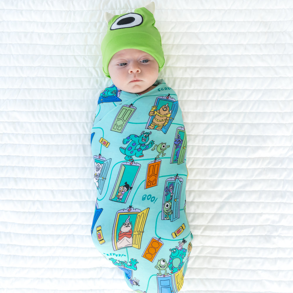 Top view image of baby laying down with in the Disney Monsters, Inc. Scream Team Swaddle & Hat Set