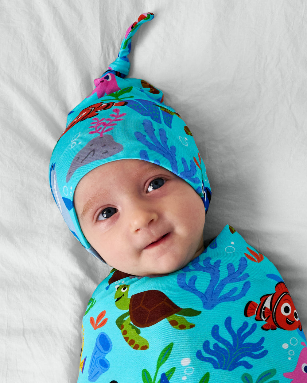 Close up of child wearing the Disney Nemo's Reef Swaddle & Hat Set