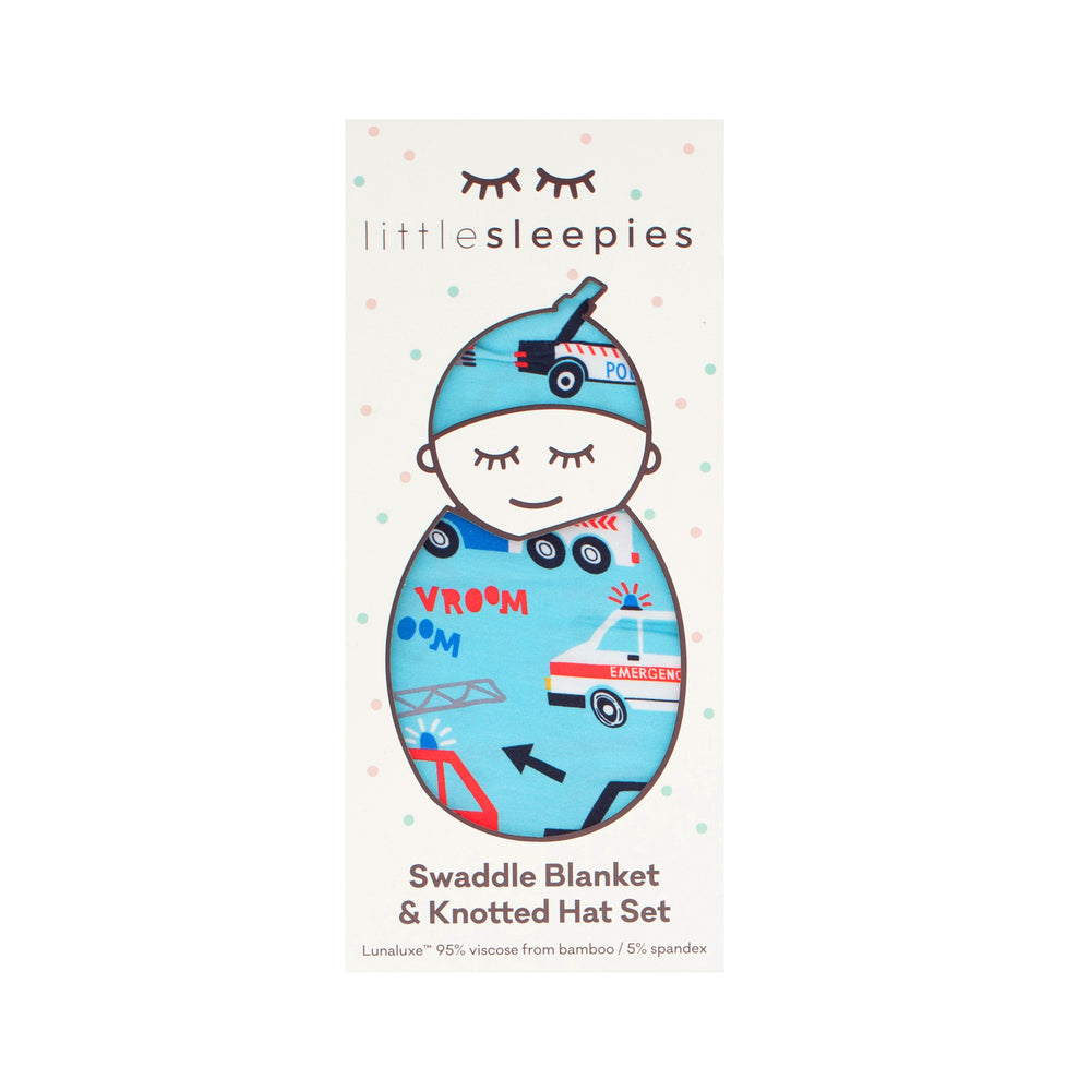 Flat lay image of a To The Rescue swaddle and hat set in Little Sleepies peek a boo packaging