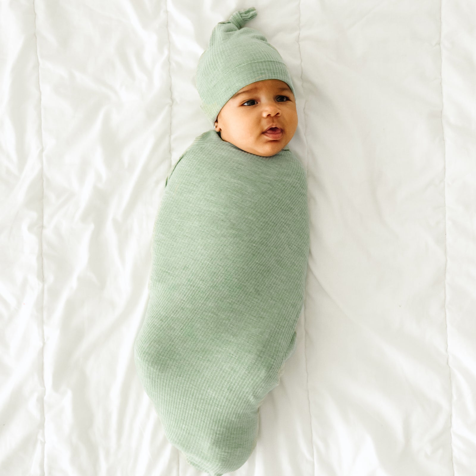 Child swaddled in a Heather Sage swaddle and hat set 