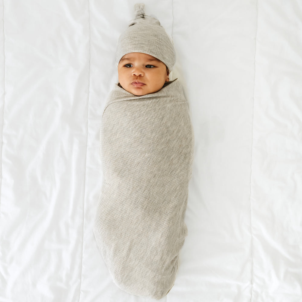 Click to see full screen - alternate image of a child swaddled in a Heather Stone Ribbed swaddle and hat set
