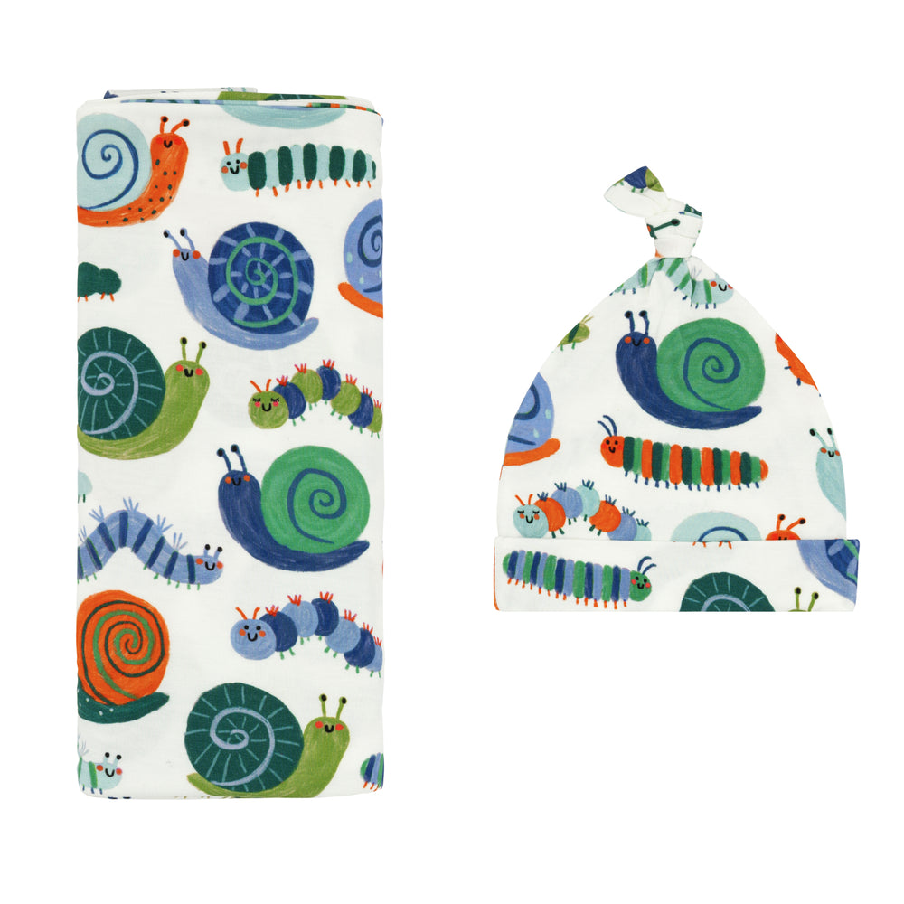 Flat lay image of an Inchin' Along swaddle & hat set