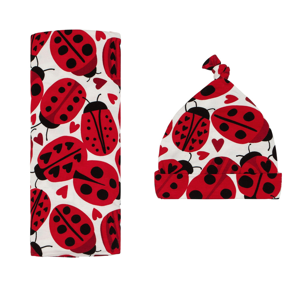 Click to see full screen - Flat lay image of a Love Bug printed swaddle and hat set
