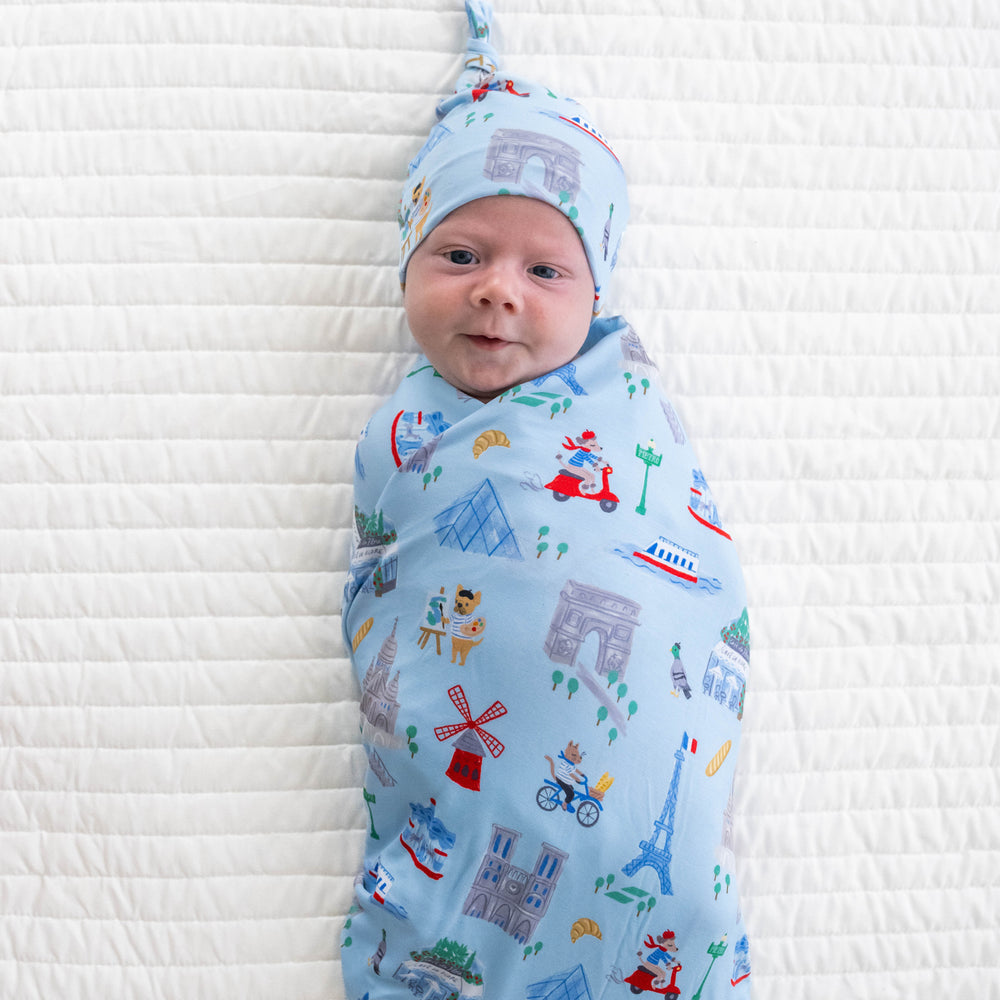 Top view image of baby wearing the Blue Weekend in Paris Swaddle & Hat Set 