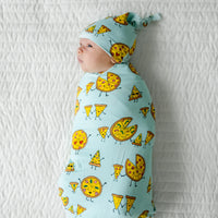 Child laying on a bed wearing a Pizza Pals swaddle and hat set