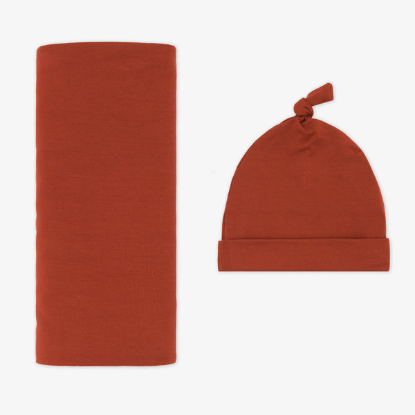 Flat lay image of a Cozy Rust swaddle and hat set