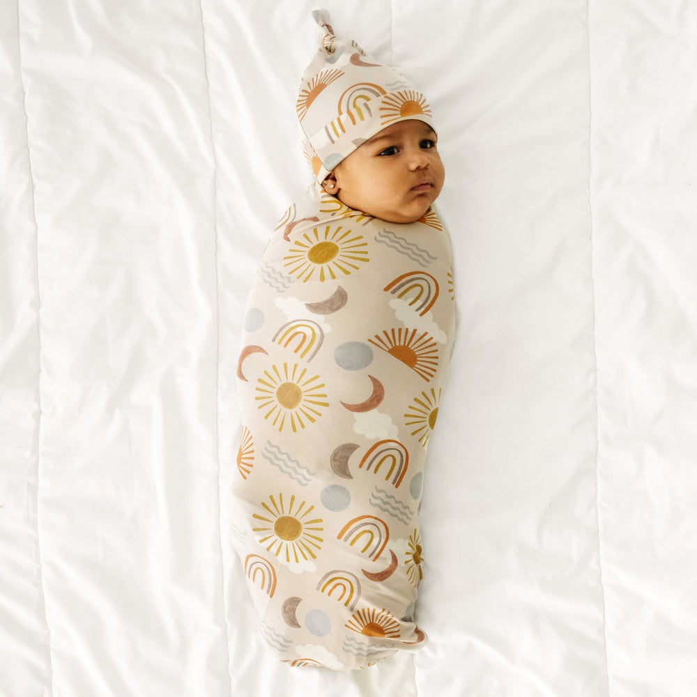 Child swaddled in a Desert Sunrise swaddle and hat set