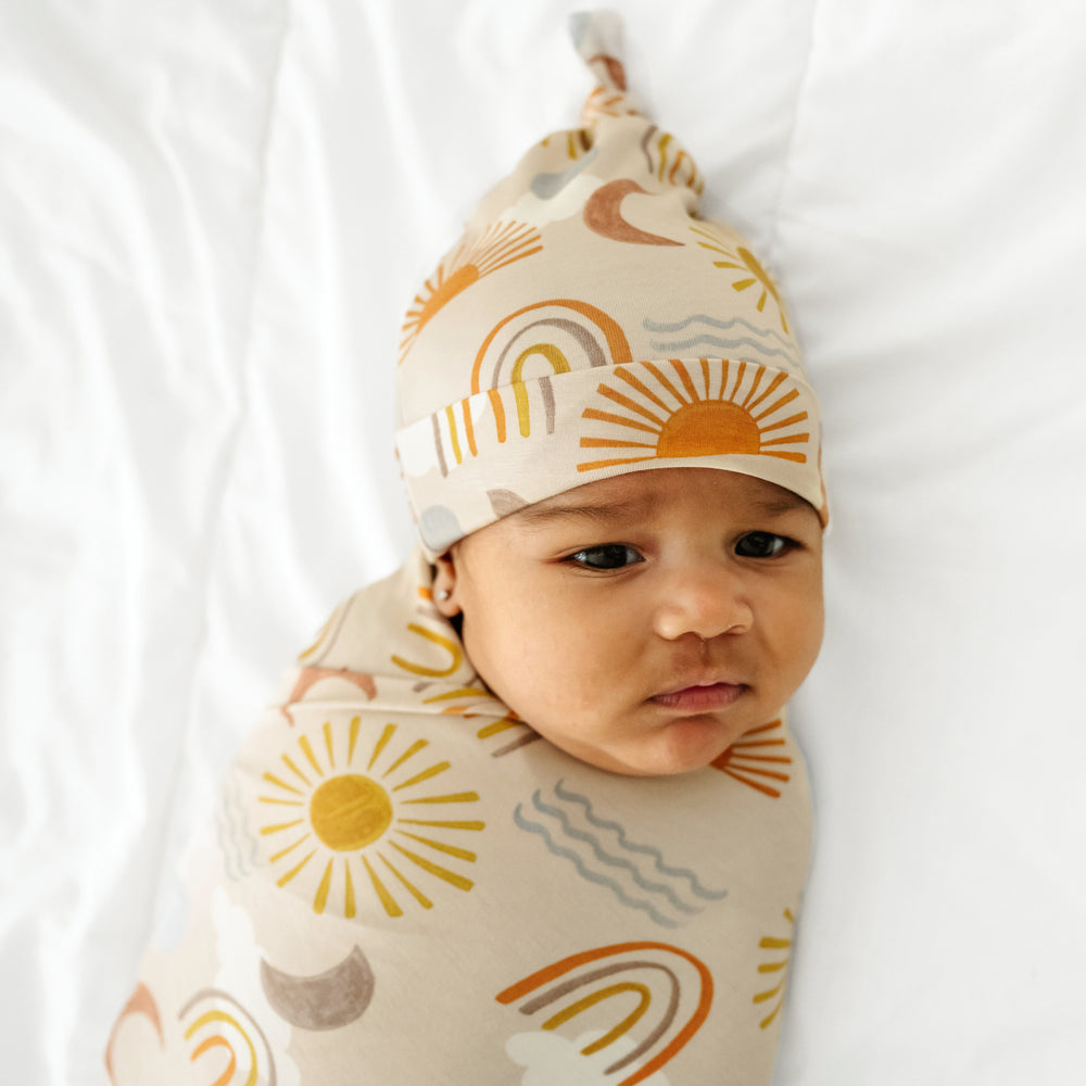 close up image of a child swaddled in a Desert Sunrise swaddle and hat set