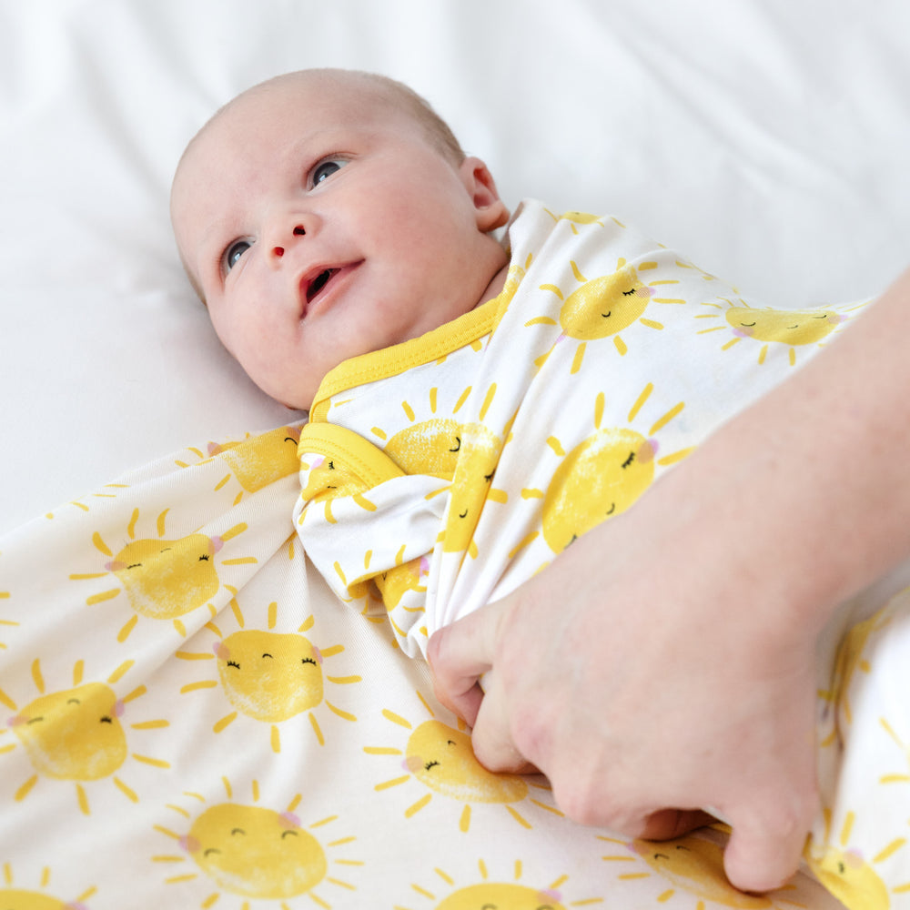 baby being actively swaddled in a sunshine swaddle