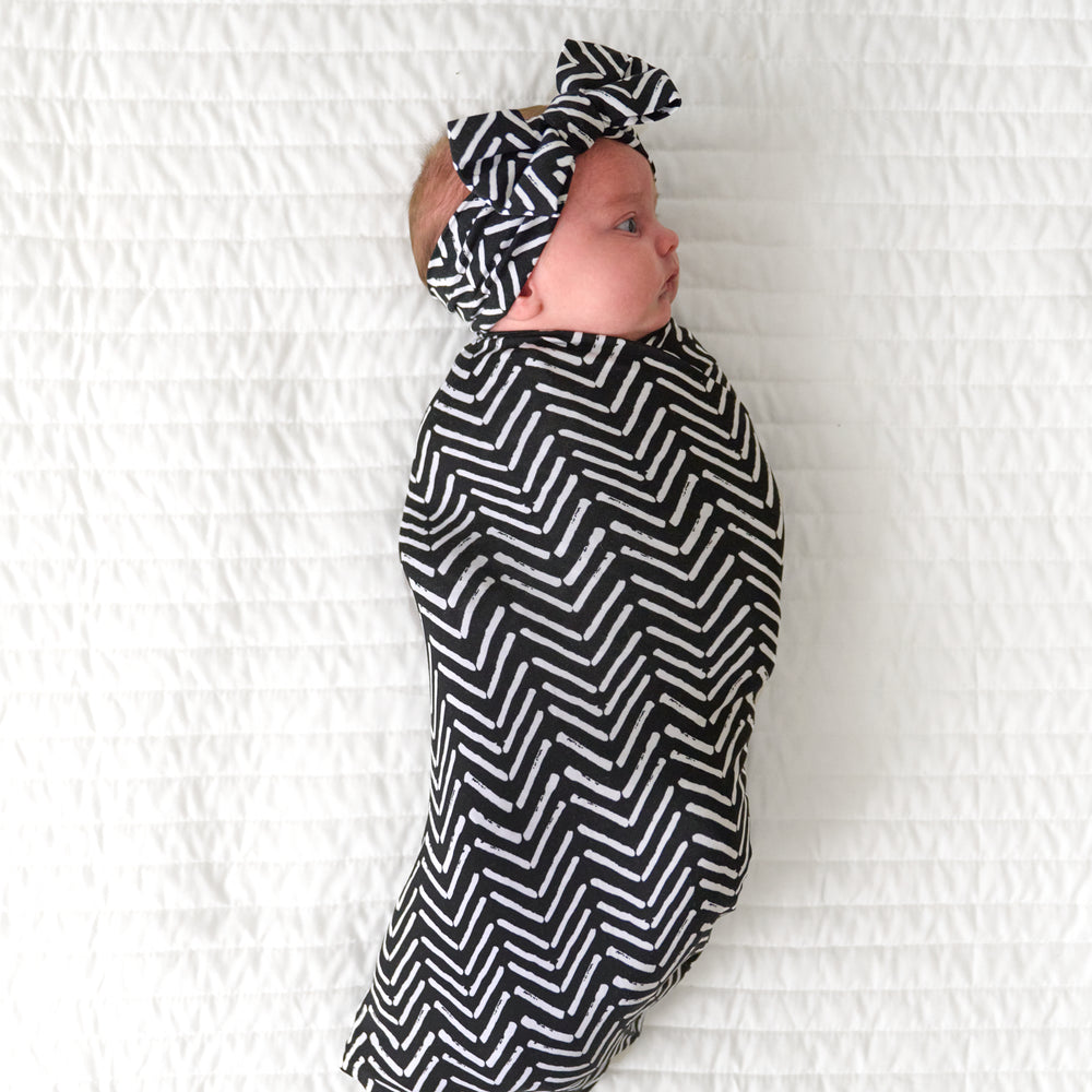 Child swaddled in a Monochrome Chevron swaddle and luxe bow headband set
