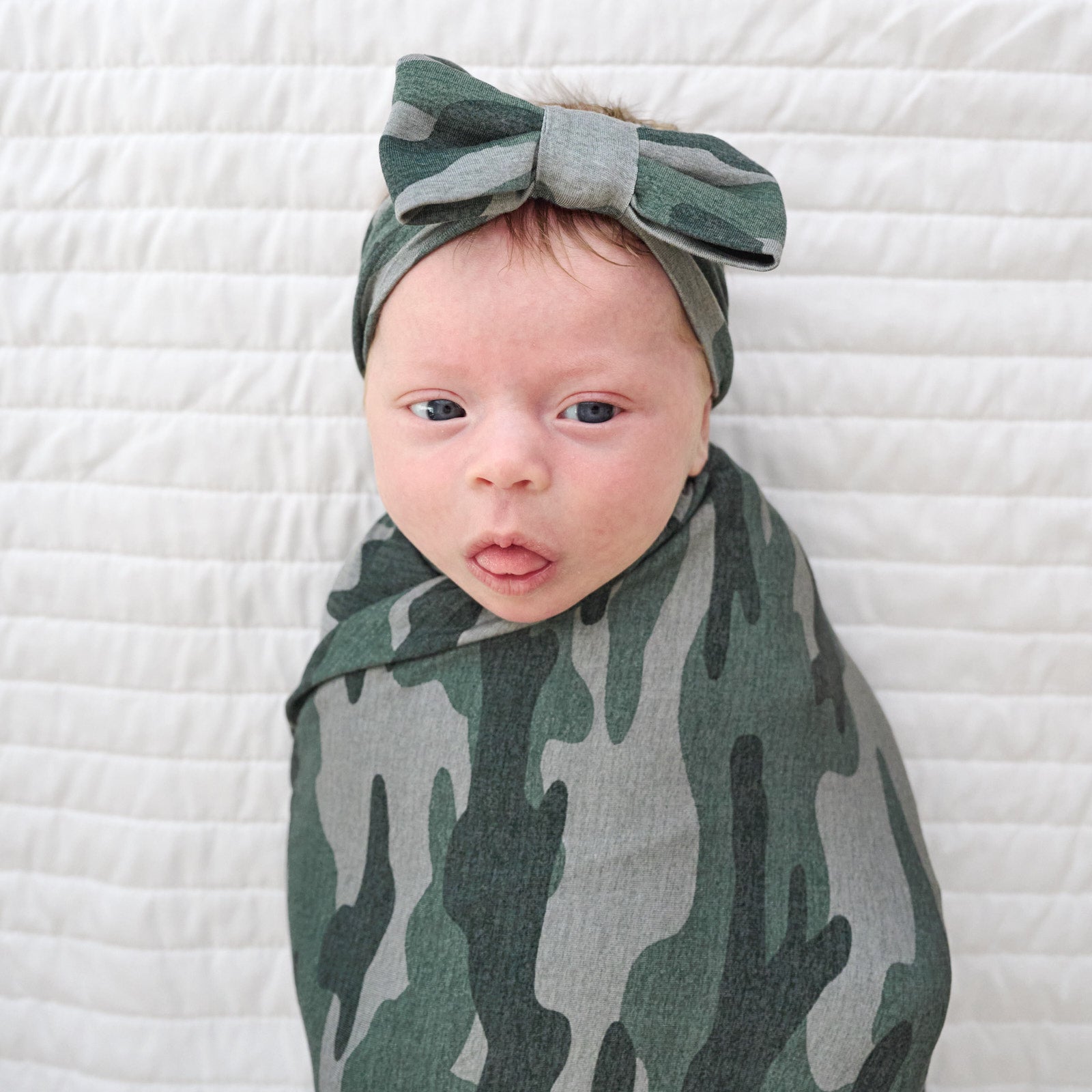 Top view image of baby in the Vintage Camo Swaddle & Luxe Bow Headband Set