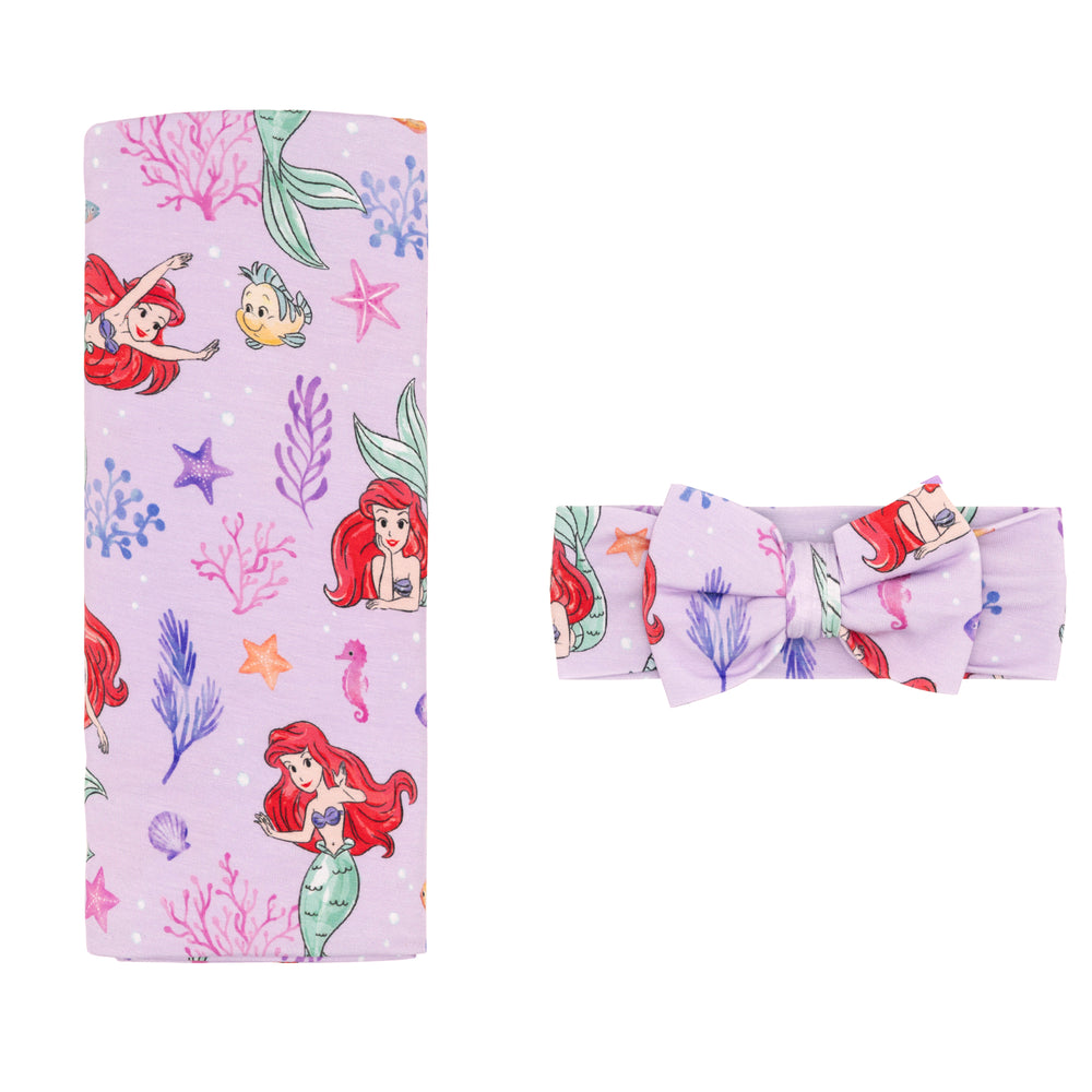Flat lay image of a Disney Part of Her World swaddle and luxe bow headband set