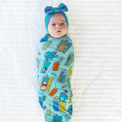 Top view image of baby laying down while in the Disney Monsters, Inc. Scream Team Swaddle & Luxe Bow Headband Set