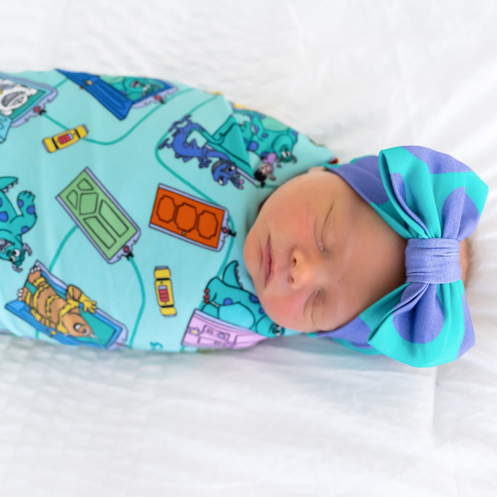 Close up top view image of baby sleeping while in the Disney Monsters, Inc. Scream Team Swaddle & Luxe Bow Headband Set