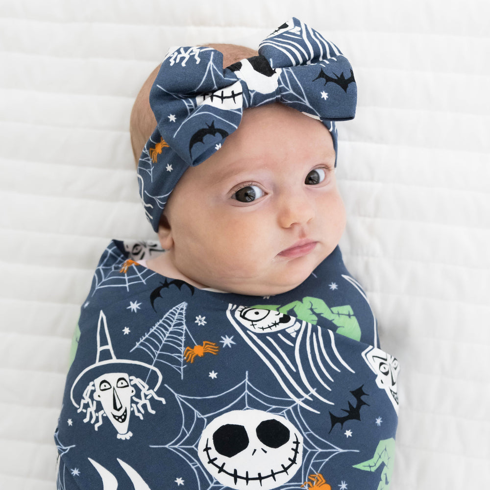 Close up top view image of baby laying down in the Disney Jack & Crew Swaddle & Luxe Bow Headband Set