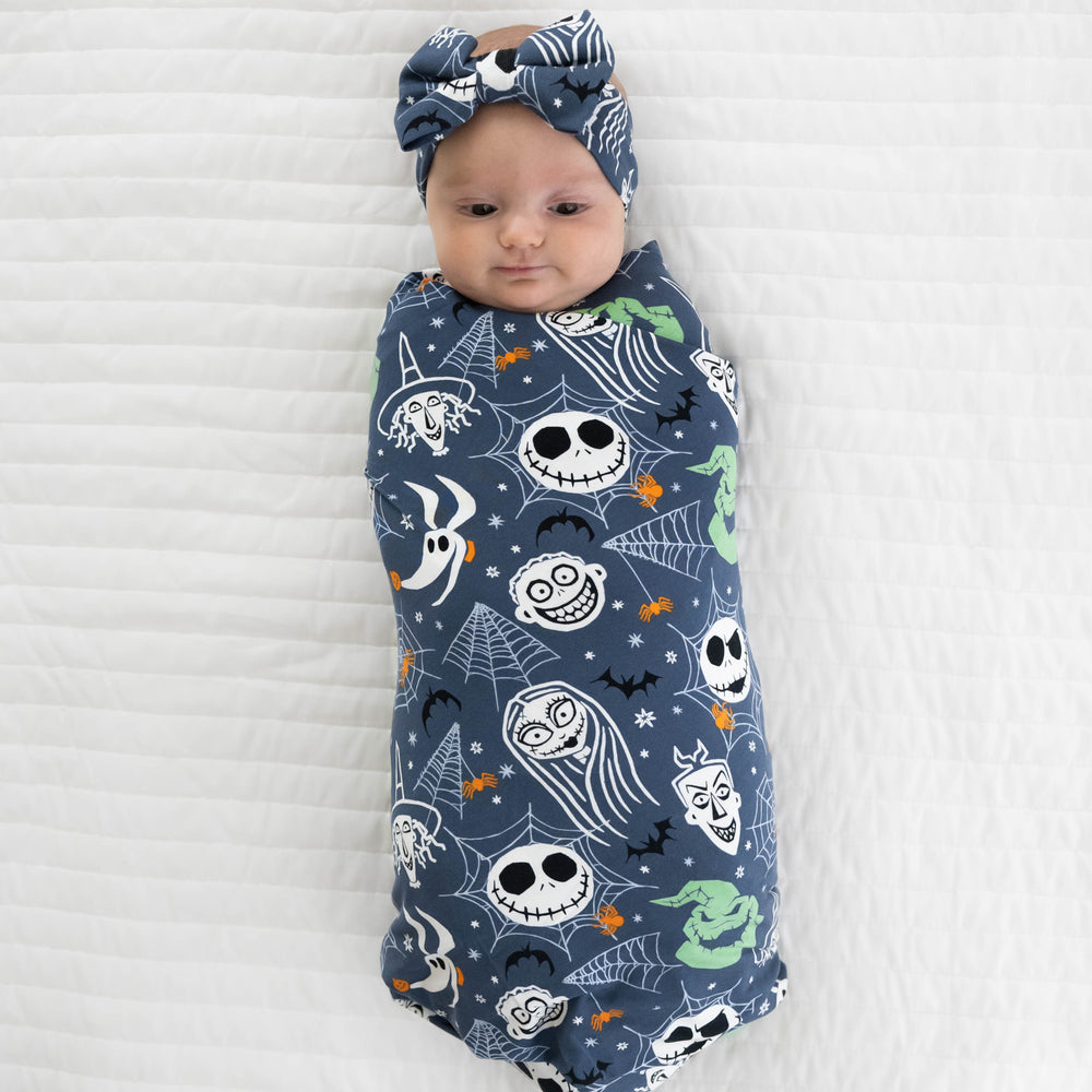 Top view image of baby laying down in the Disney Jack & Crew Swaddle & Luxe Bow Headband Set