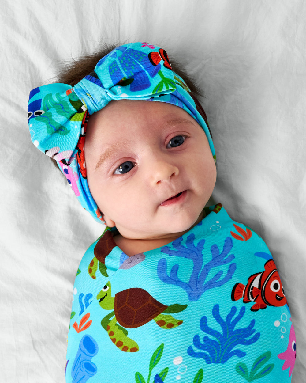 Close up of child in the Disney Nemo's Reef Swaddle & Luxe Bow Headband Set
