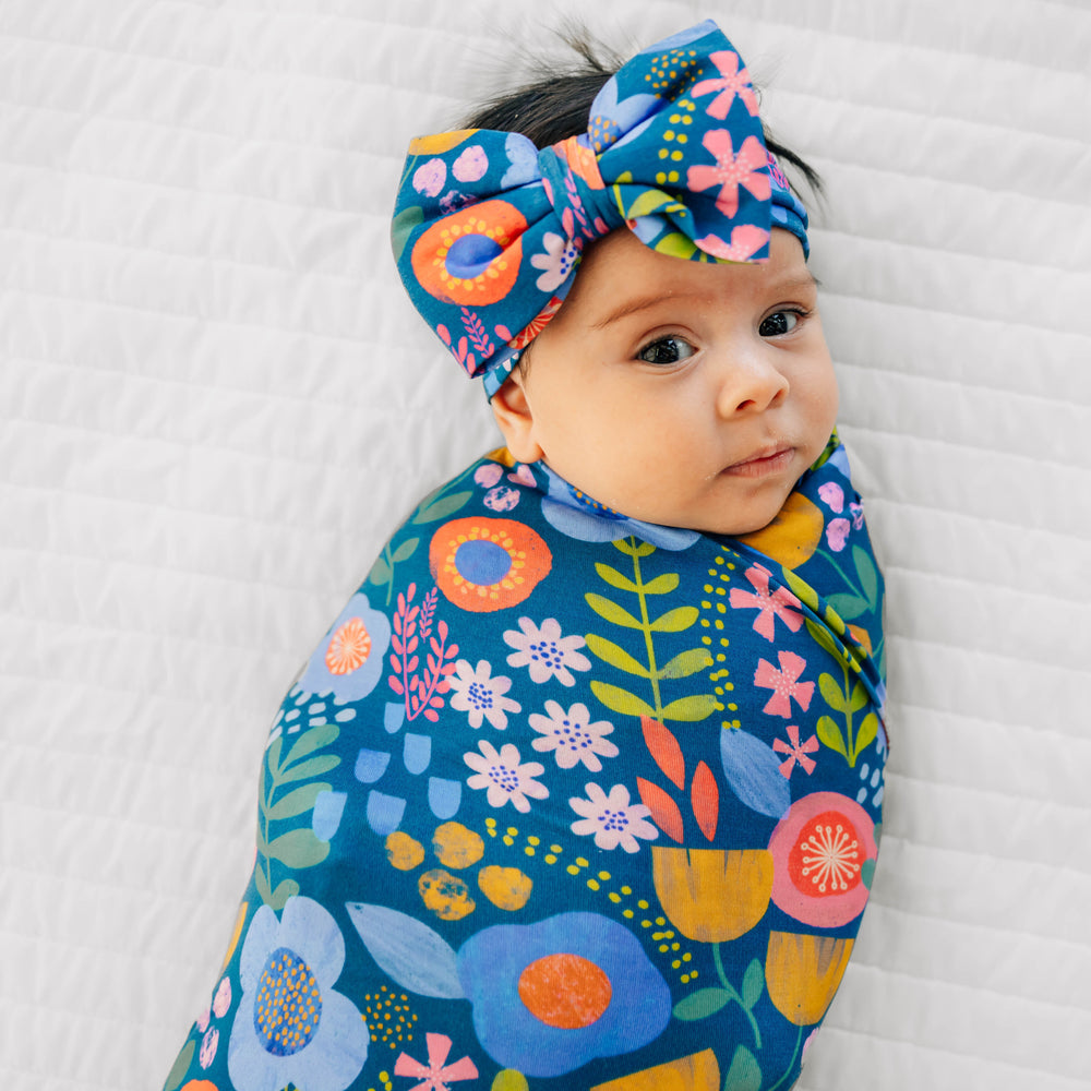 Close up image of baby wearing the Folk Floral Swaddle & Luxe Bow Headband Set