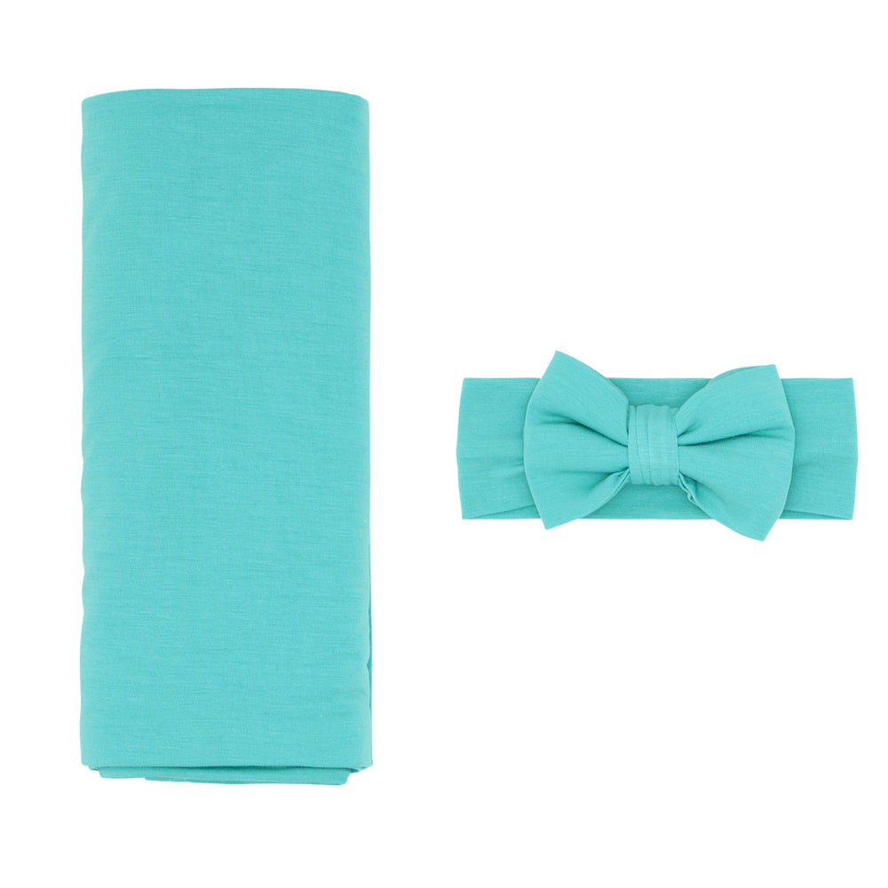 Flat lay image of a Glacier Turquoise swaddle and luxe bow set