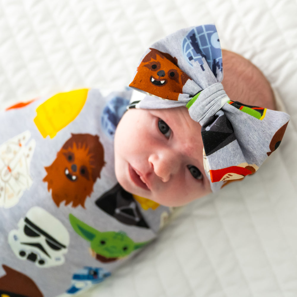 Close up image of an infant swaddled in a Legends of the Galaxy swaddle & luxe bow headband set