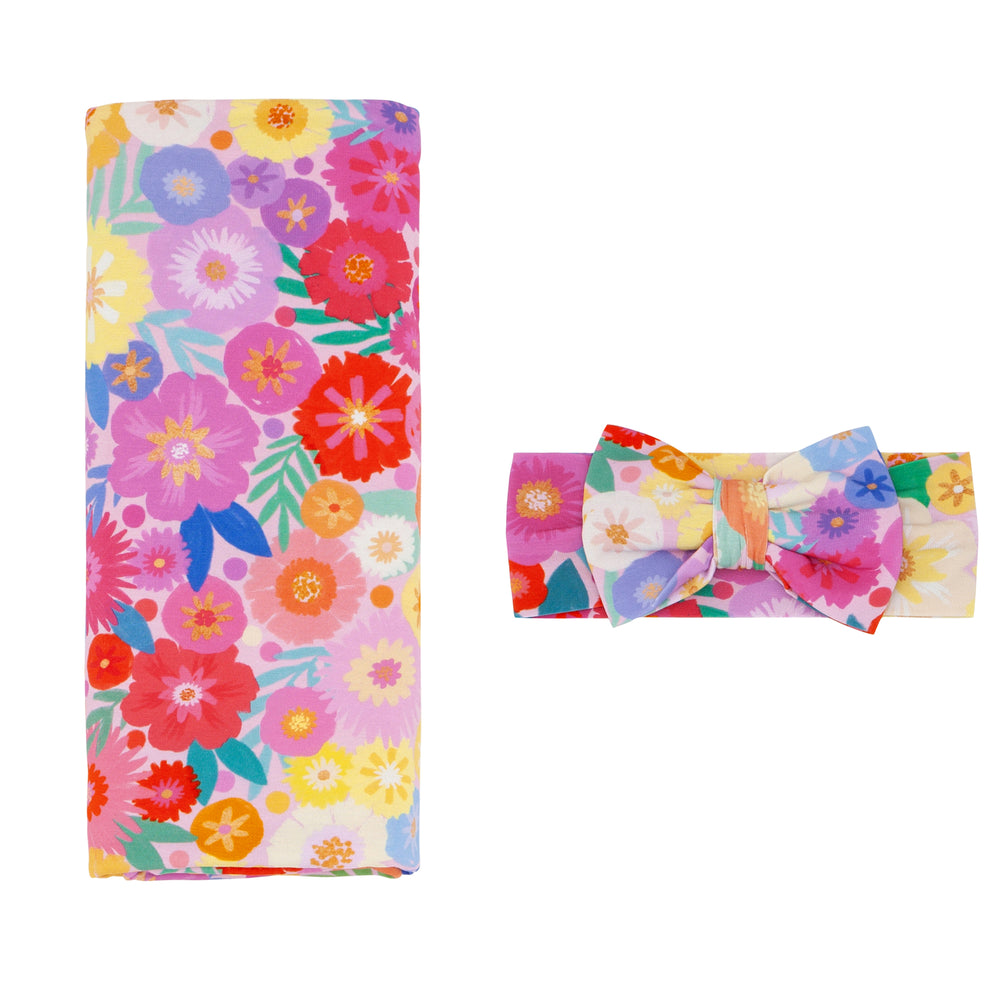 Flat lay image of a Rainbow Blooms swaddle and luxe bow headband set
