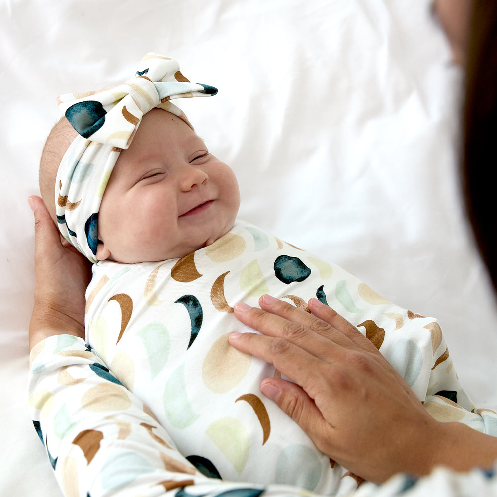 baby smiling wearing luna neutral swaddle with luxe bow headband