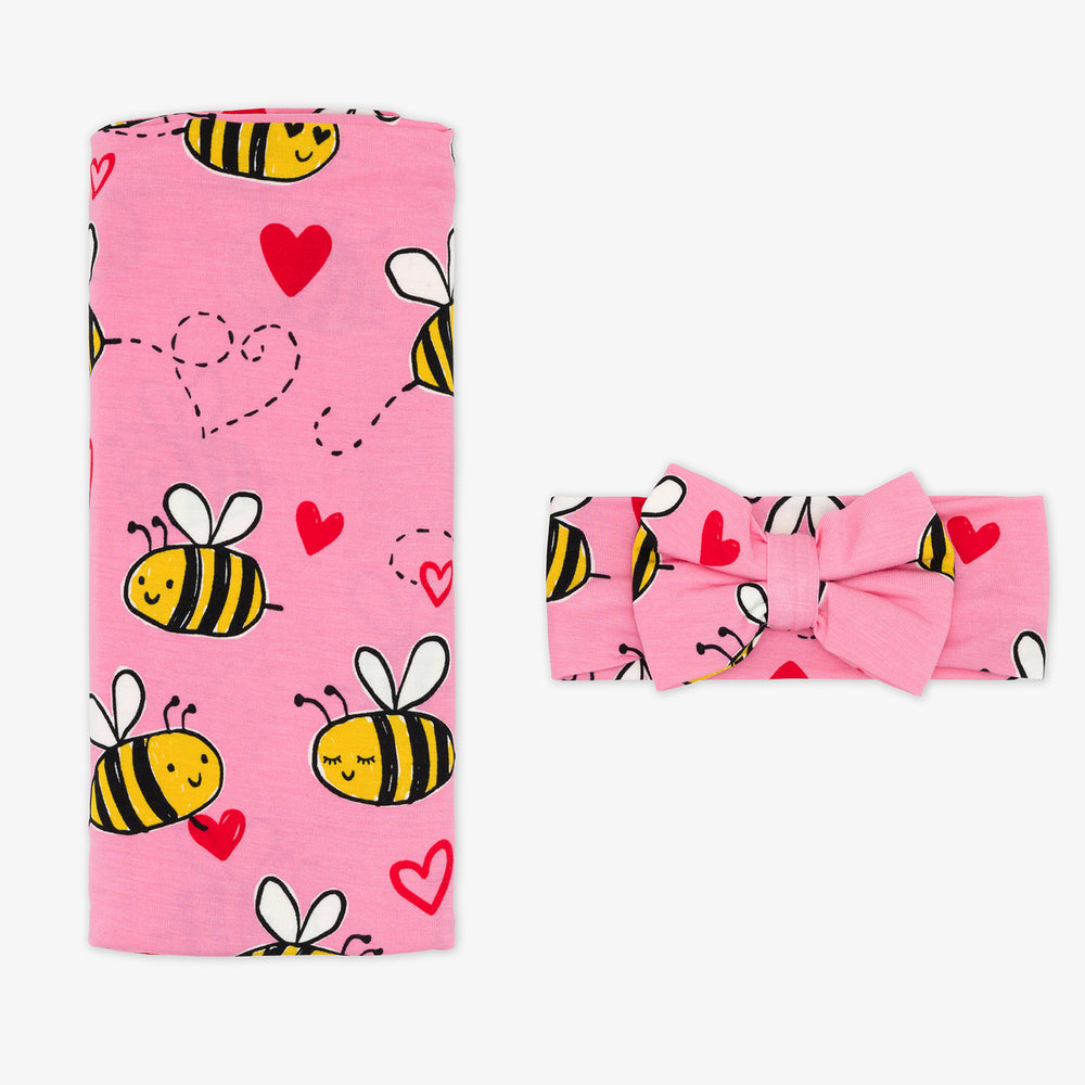 Flat lay image of a Pink Bee Mine swaddle and luxe bow headband set