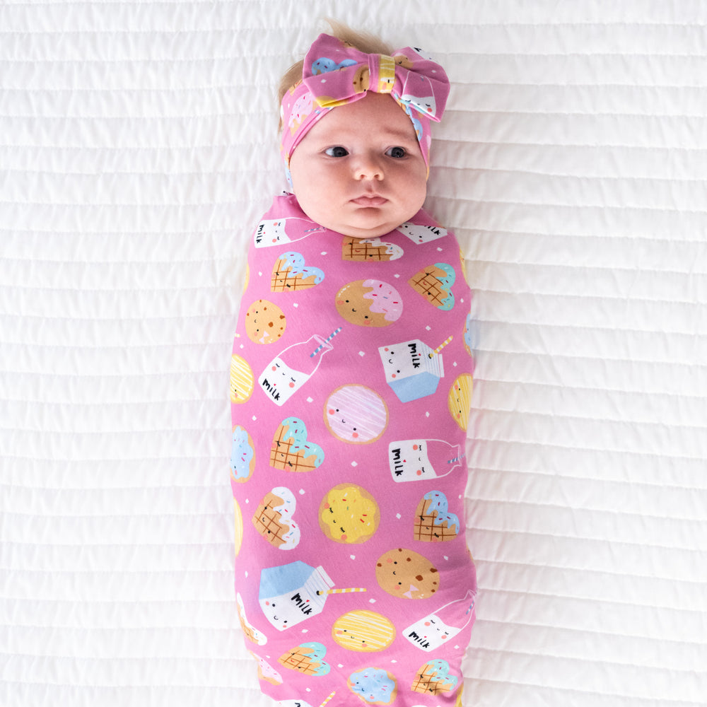 baby lying on blanket wearing cookies & milk swaddle with headband