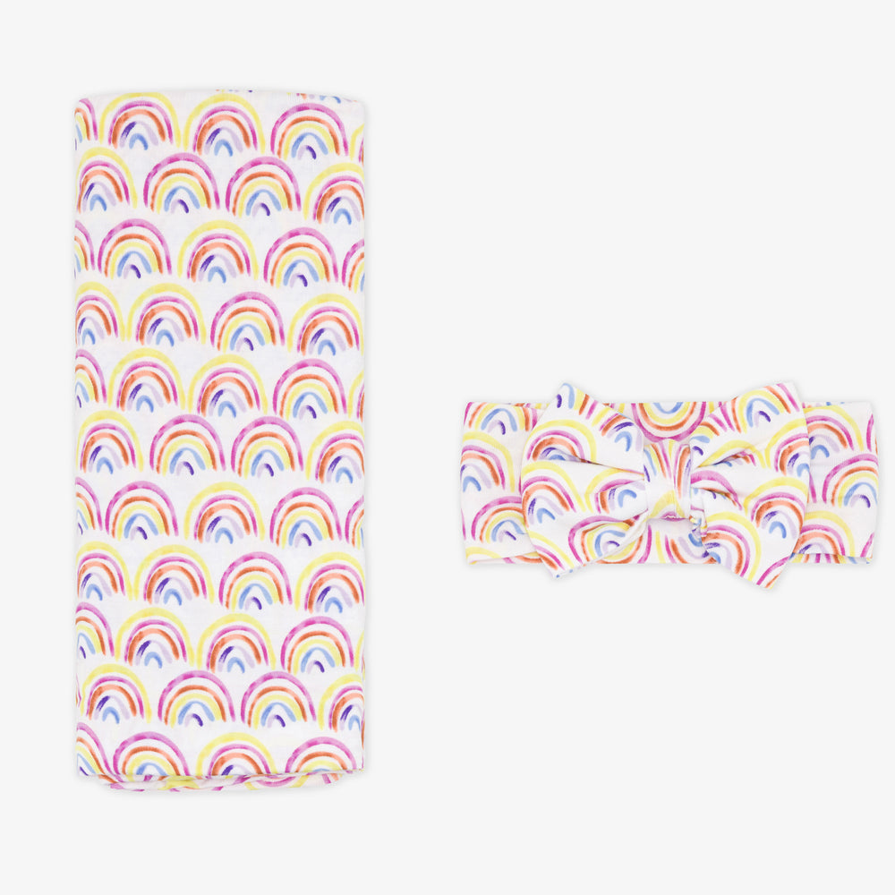 Flat lay image of a Pastel Rainbows Swaddle and luxe bow Headband set