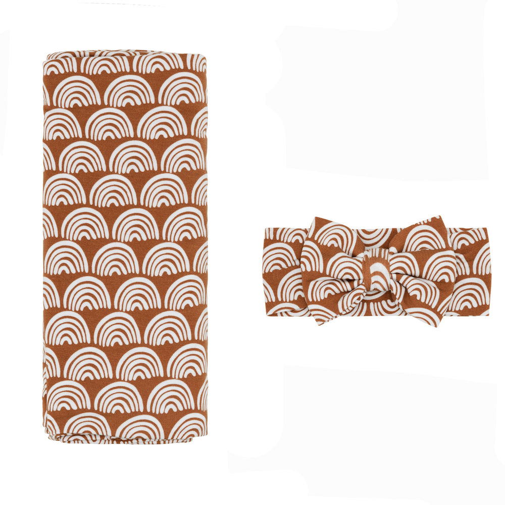 Flat lay image of a Rust Rainbows Swaddle and luxe bow Headband set