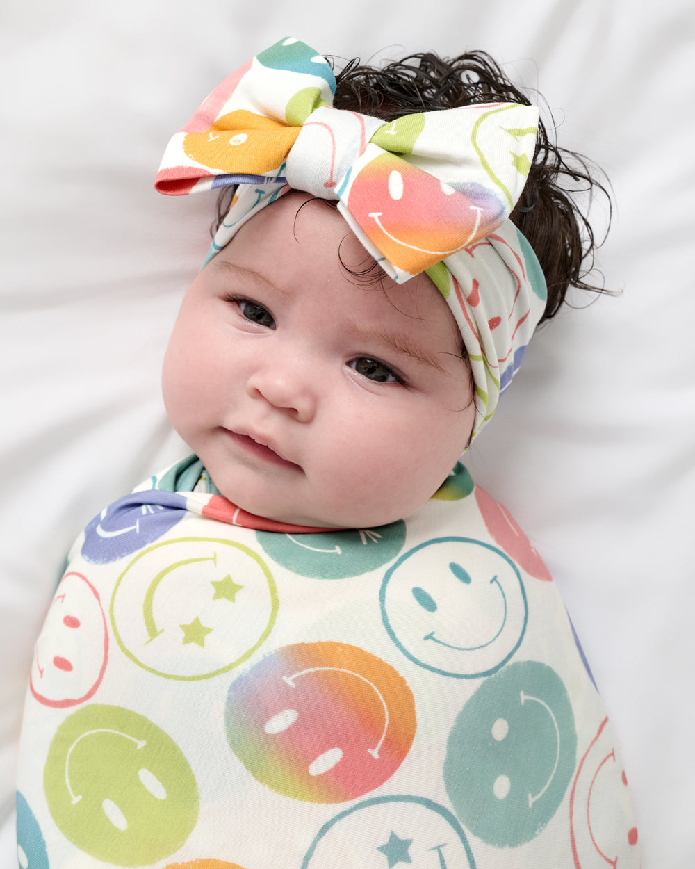 Close up of baby wearing the Positive Vibes Swaddle & Luxe Bow Headband Set