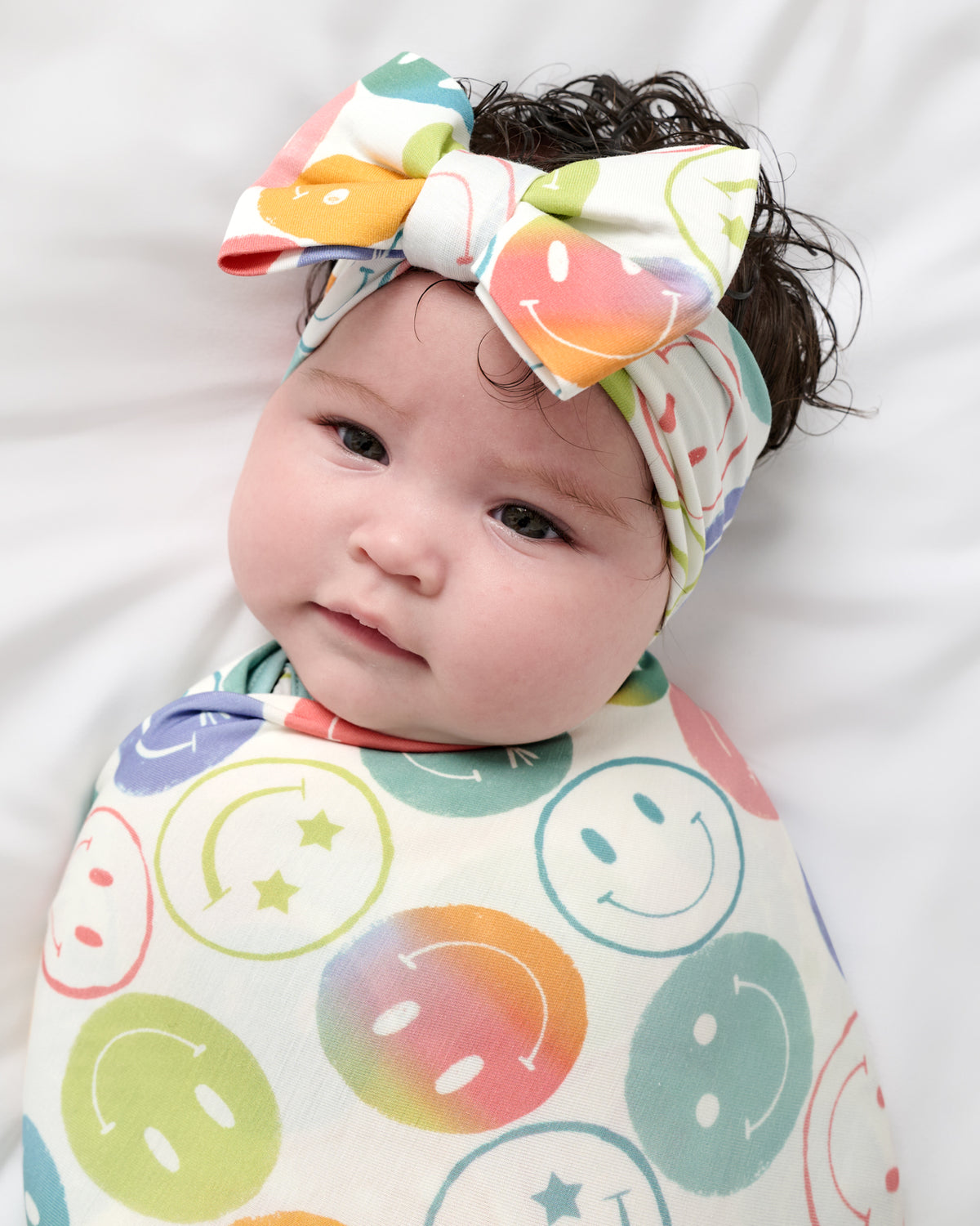 Close up of baby wearing the Positive Vibes Swaddle & Luxe Bow Headband Set