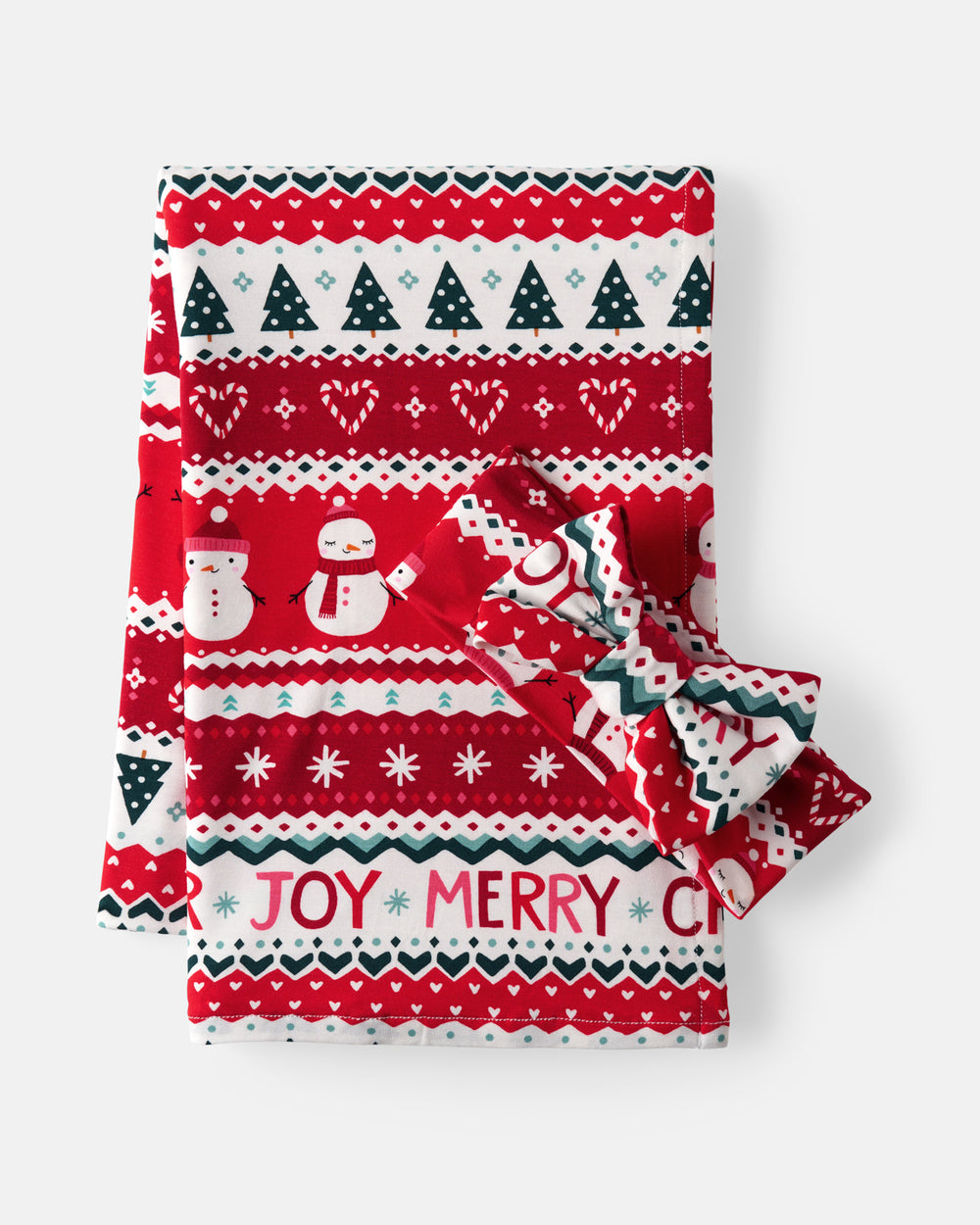 A folded Christmas-themed blanket, featuring a festive red and white pattern with snowmen, snowflakes, pine trees, and the words 'JOY MERRY'. A matching red and white bow is tied around the folded edges, set against a clean light gray background.