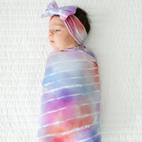 Infant swaddled in a Pastel Tie Dye Dreams swaddle & luxe bow headband set