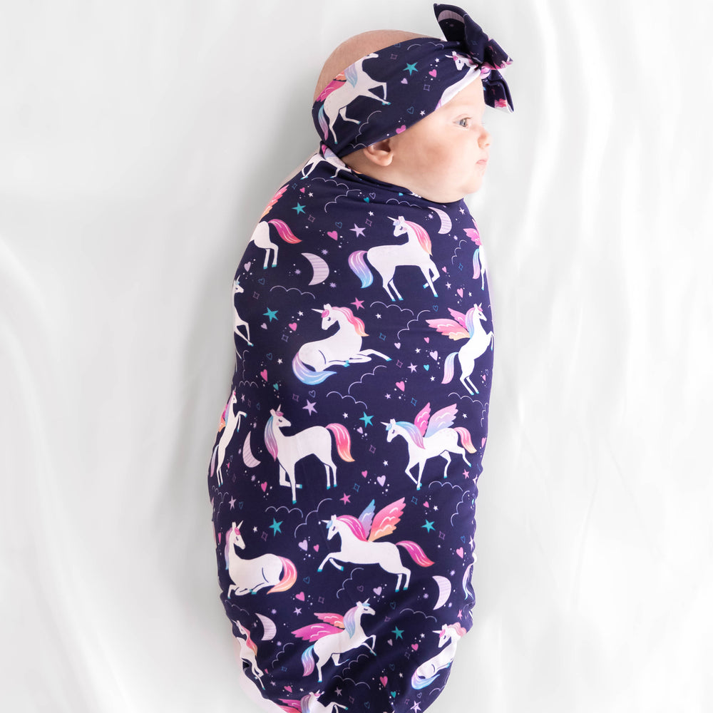 Top view on baby laying while wrapped in the Magical Skies Swaddle & Luxe Bow Headband Set