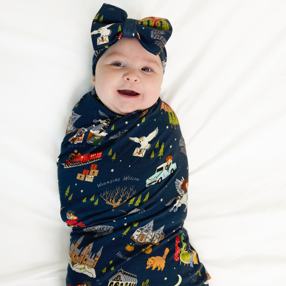 Child swaddled in an Evening at Hogwarts swaddle and luxe bow headband set