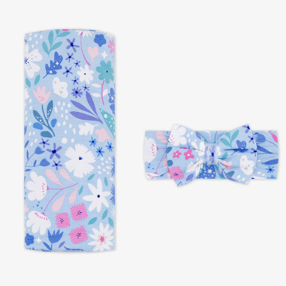 Flat lay image of a Magical Meadow swaddle and luxe bow headband set