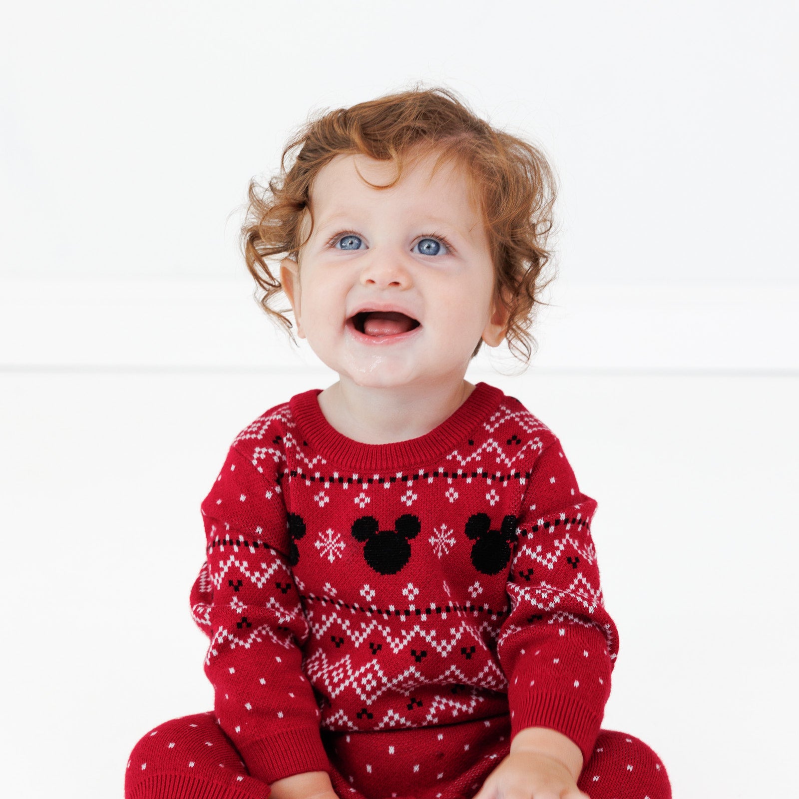 Image of a child sitting on the ground wearing a Vintage Mickey Fair Isle Sweater Romper