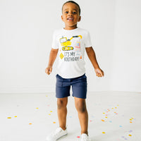 Child playing wearing Birthday Builders construction graphic tee paired with navy shorts