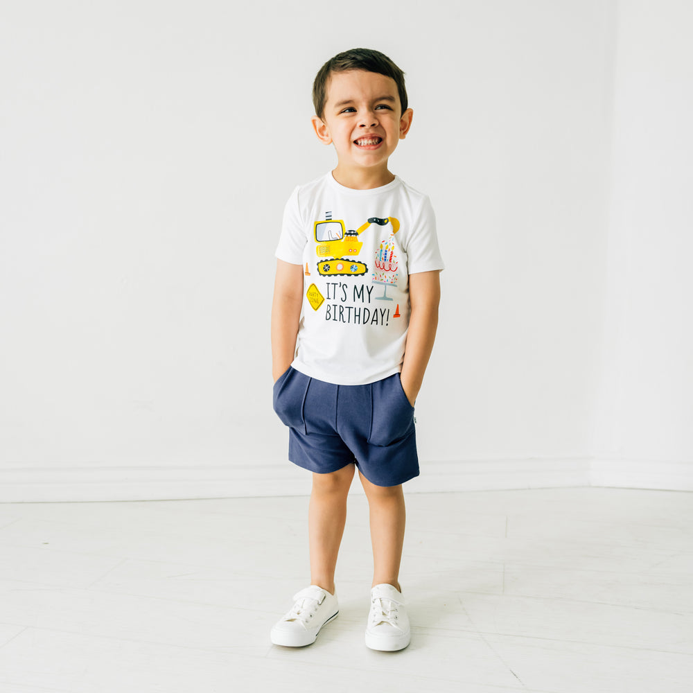 Alternate image of a child posing wearing Birthday Builders construction graphic tee paired with navy shorts