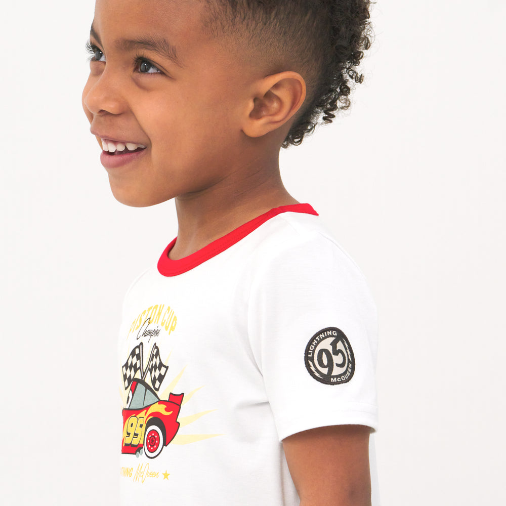Close up side view image of a child wearing a Lightning McQueen graphic tee