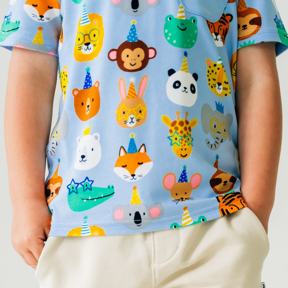 Close up image of a child wearing Blue Party Pals pocket tee paired with Bone shorts