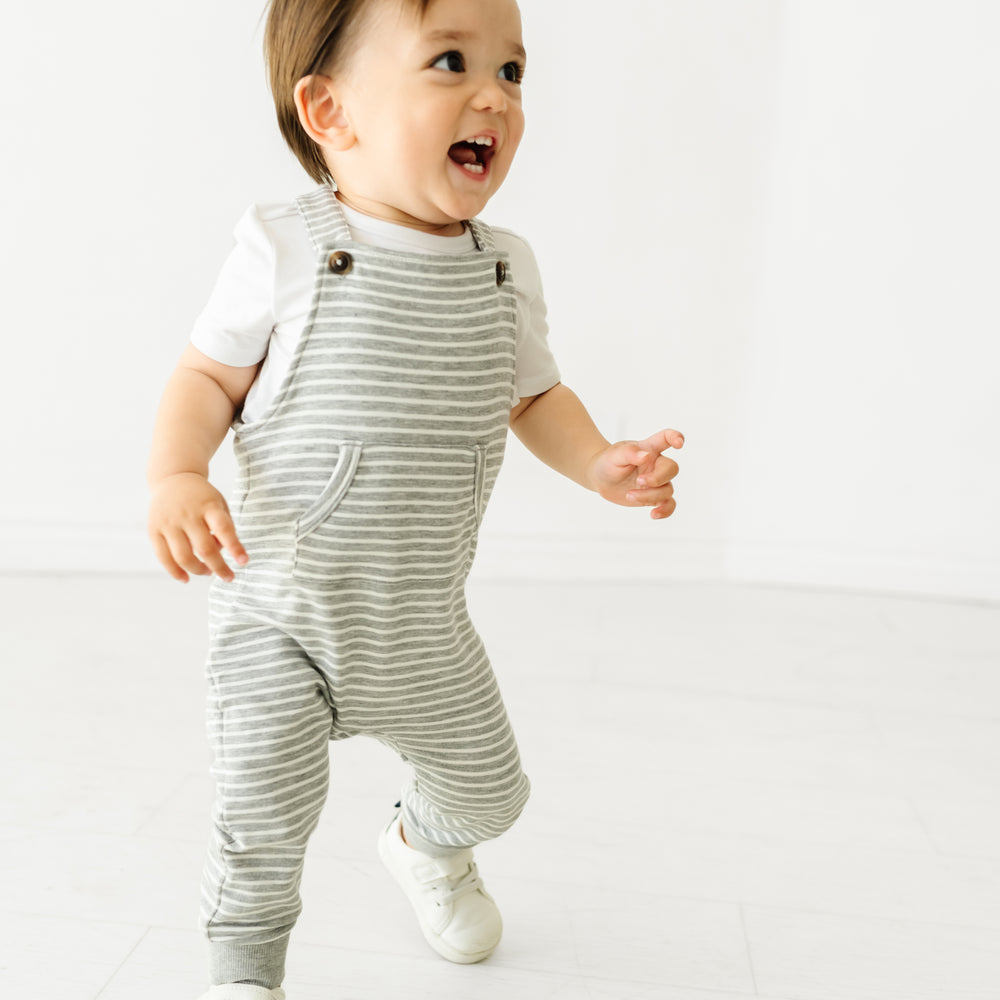 Child running, wearing Heather Gray Stripes overalls and coordinating Play bodysuit