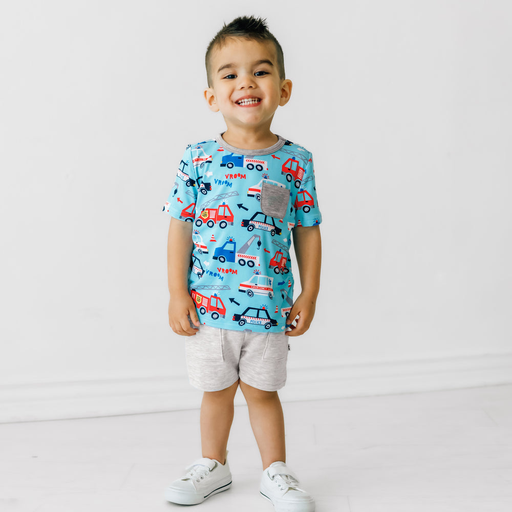 Child posing wearing a To The Rescue pocket tee paired with light heather gray shorts