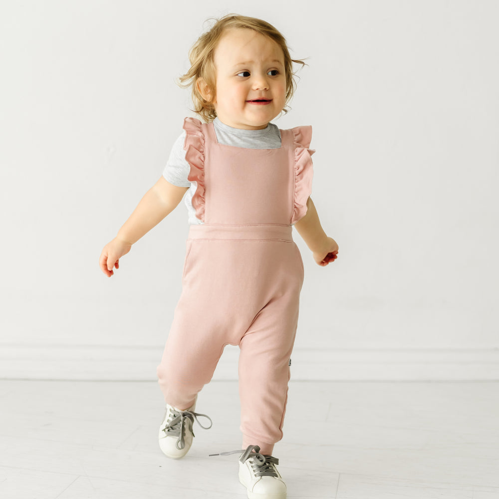 Child wearing a Mauve Blush ruffle overall and coordinating Play top