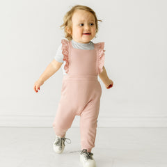 Child wearing a Mauve Blush ruffle overall and coordinating Play top