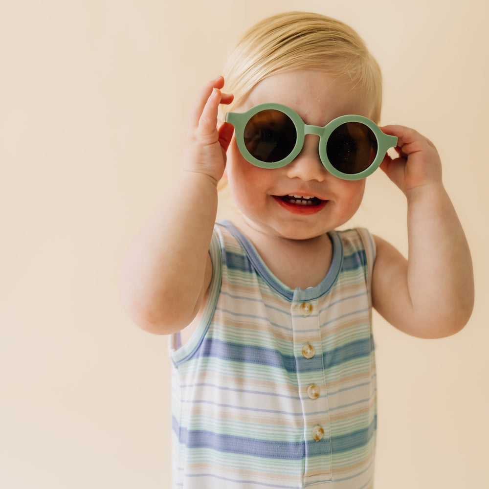 Close up image of a child sitting wearing a Surf Stripe tank button romper showing the button details